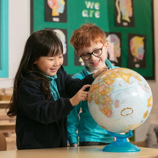 Two young students looking at a Globe