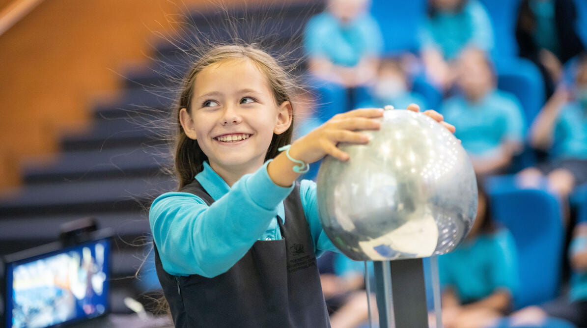Student with their hands on a Van de Graaff generator