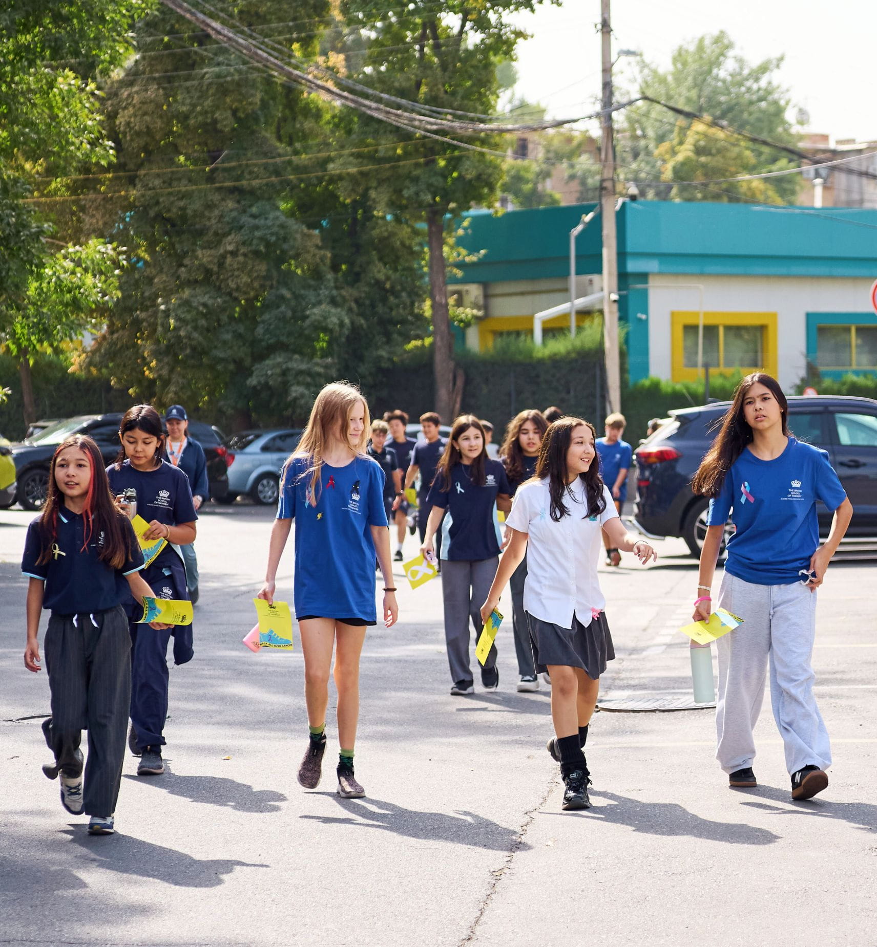 BST students holding colourful signs and wearing wristbands during the Walk All Over Cancer event in Tashkent.