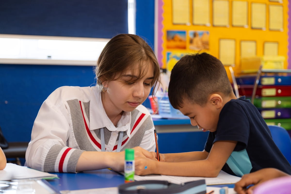 A teacher and a student work together at a classroom table at The British School of Tashkent. The teacher provides personalised guidance during a hands-on task while the student focuses on the activity, surrounded by colourful learning materials. The scene reflects the human connection, responsive teaching and real-time support at the heart of BST and the Nord Anglia Education approach, highlighting the essential skills that AI cannot replace.