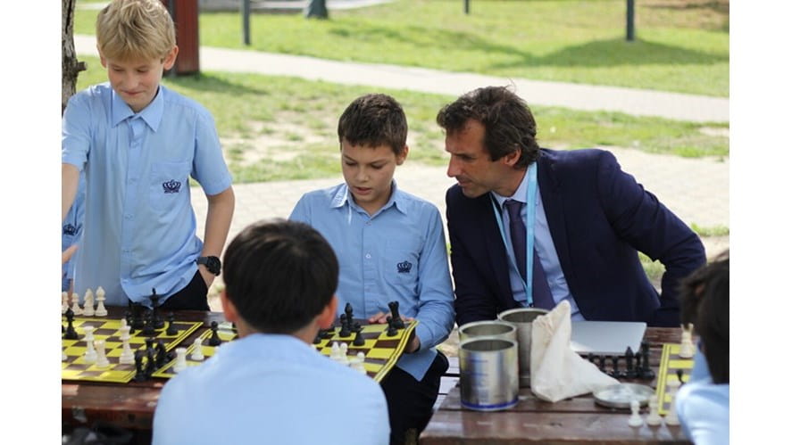Kids talking to teacher over a game of chess