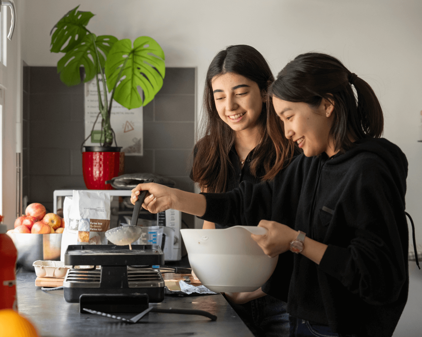 Two boarding students cooking together in their residence kitchen, enjoying independence, friendship, and life skills at Collège du Léman.
