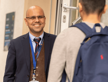 A CDL Boarding House Parent warmly welcoming a student, showcasing personal connection and pastoral care.