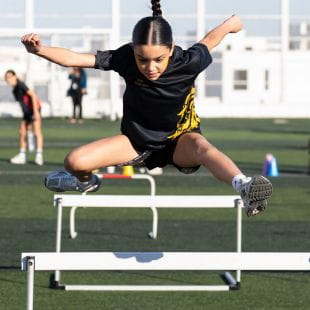 NAS Dubai student jumping hurdles on a large pitch
