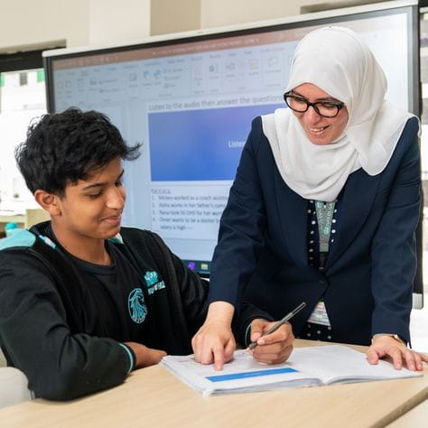 Teacher guiding a student through written work during a one‑to‑one classroom lesson.