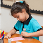 EYFS child at NAS Dubai participating in a classroom task, using learning materials at a table during an early years activity.