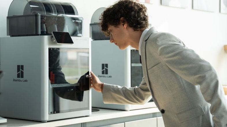 A NAS Dubai student closely examining a 3D printer while developing a design project in the DICE (Design, Innovation, Creativity and Enterprise) Lab.