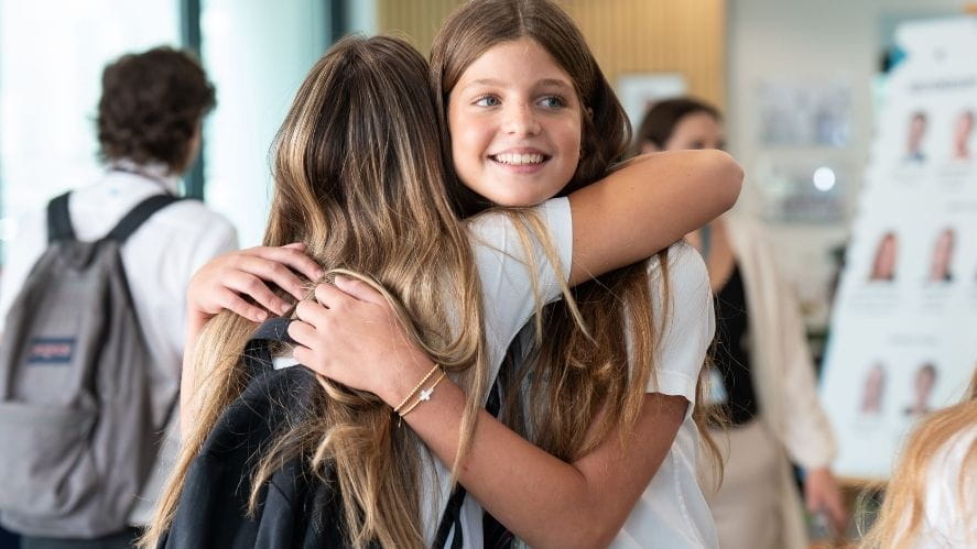 Two students embracing each other in a school setting. 