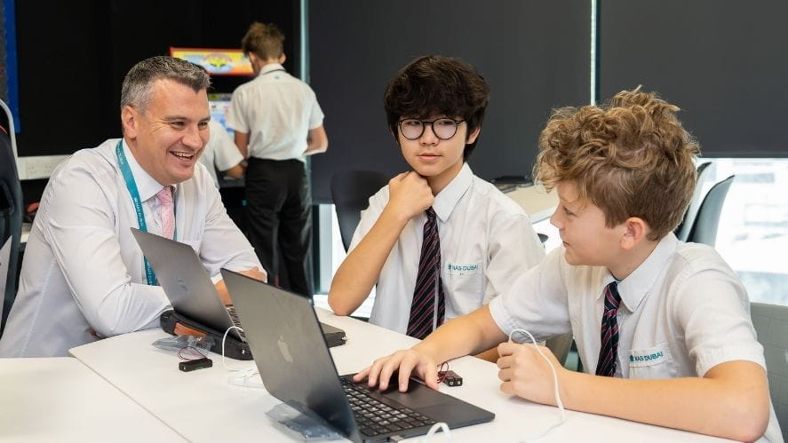 A small group discussion between students and a teacher, where conversation and reflection are the focus and technology supports rather than leads the interaction at NAS Dubai.