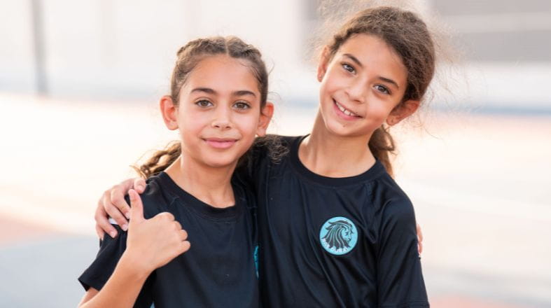 Two students embracing and posing for a picture in sports uniform