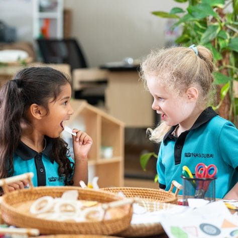 Two students smiling and crafting together in eyfs classroom