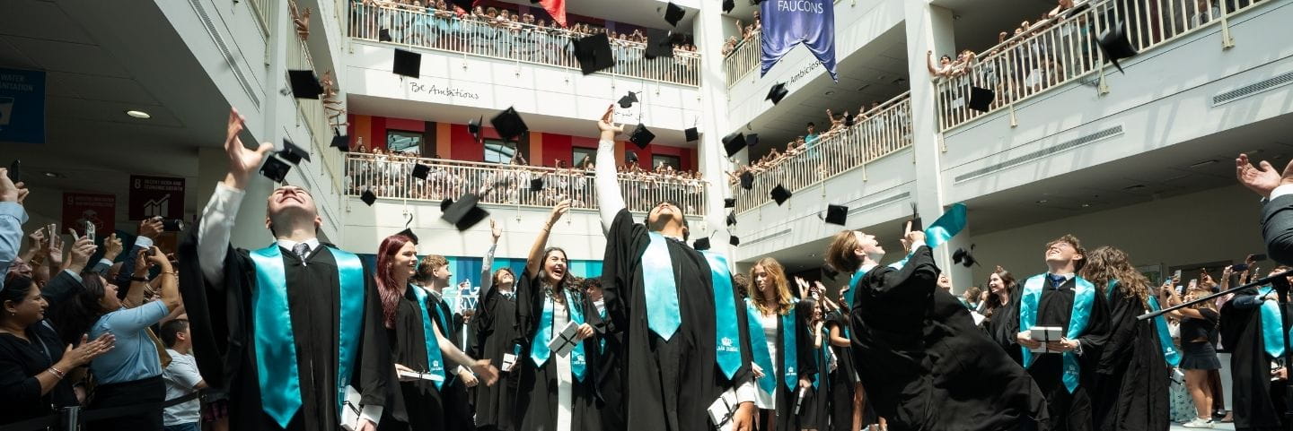 Graduating students at Nord Anglia International School Dubai celebrate by tossing graduation caps into the air during a school ceremony inside the campus atrium.