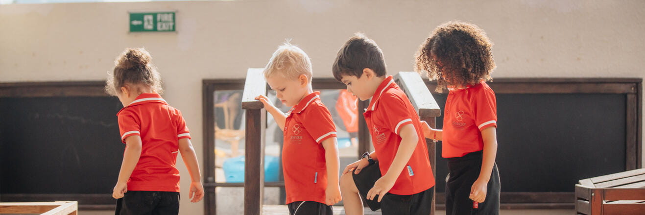 Four kindergarten students in a line wearing SISD uniforms