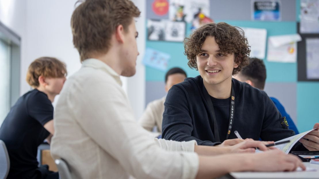 two students in a classroom looking at eachother