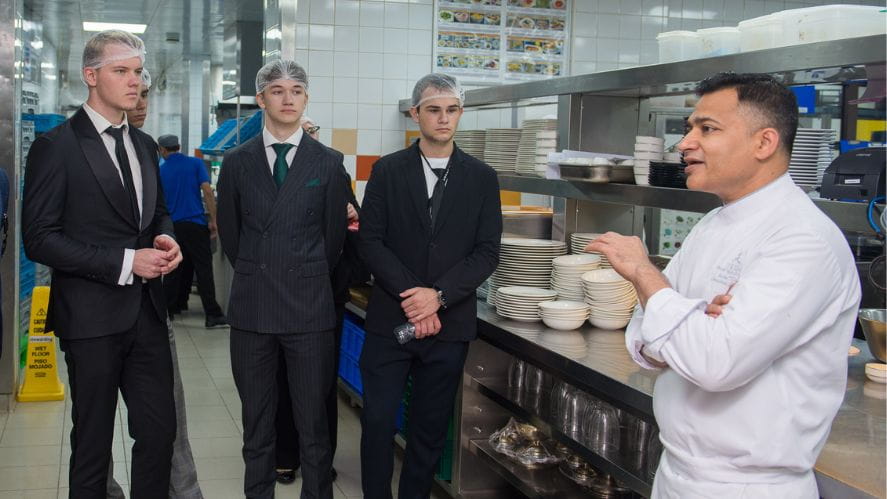 students in a kitchen speaking to a chef
