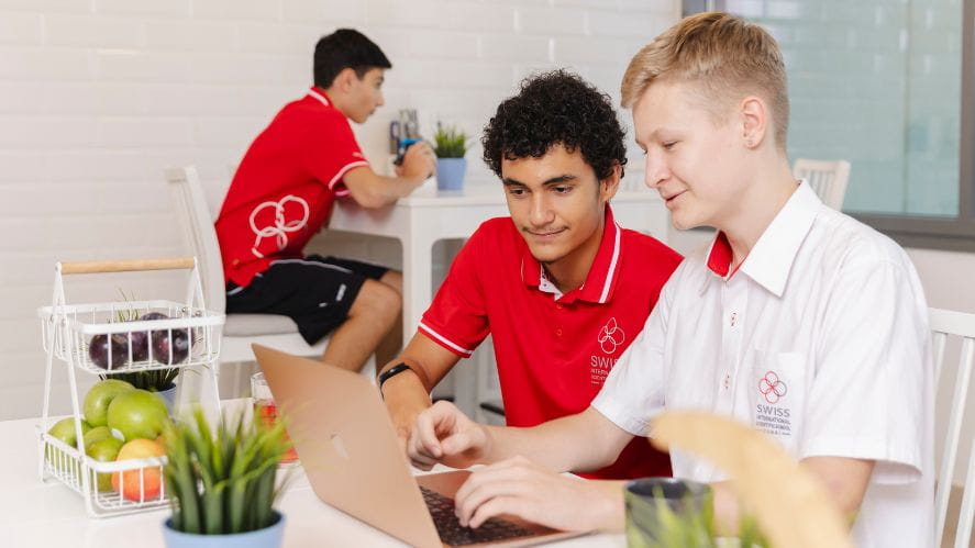 students looking at a laptop in a kitchen