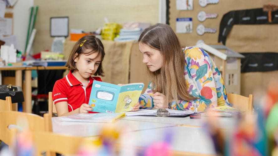 student and teacher reading a book