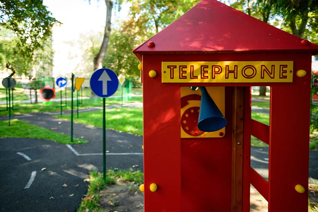 a telephone booth for kids and a park with streets in the background