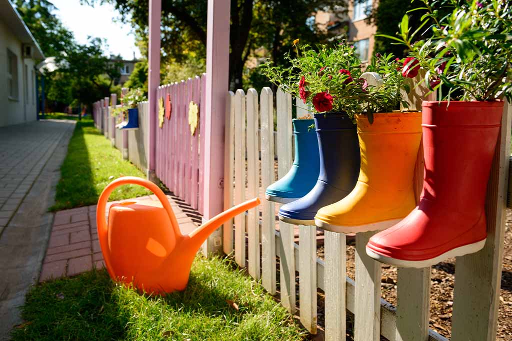 flowers in rain boots on a garden fence