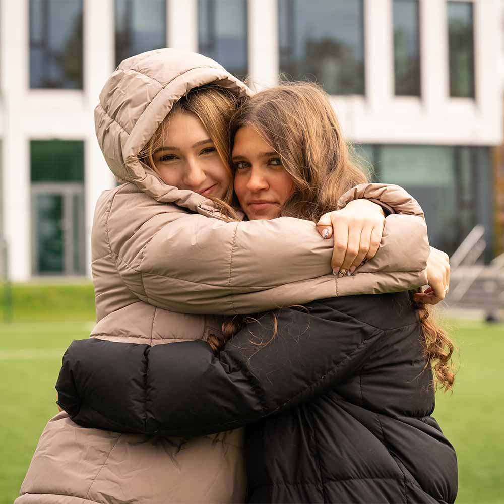 two IB students hugging on a pitch