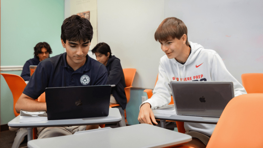 Windermere Prep students work on laptops while seated at desks in a classroom.