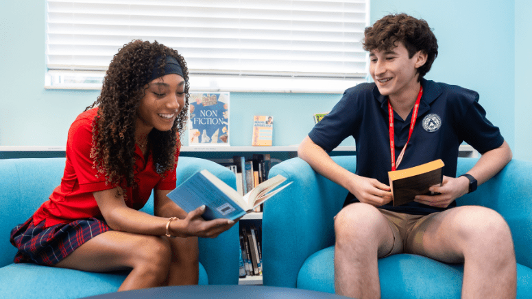 Two Windermere Preparatory School students read and discuss books together in the school library during independent learning time.