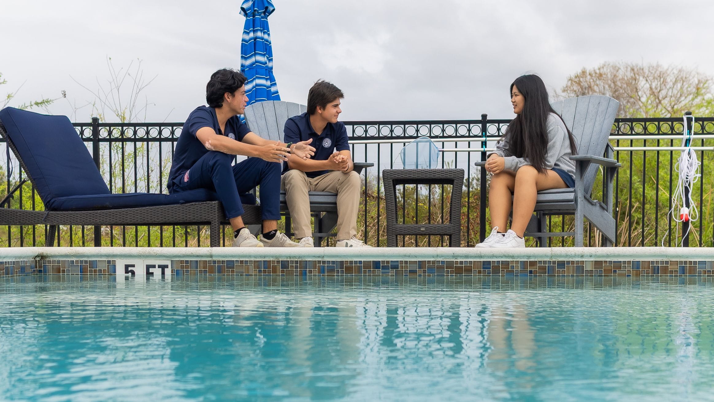 Windermere Prep students sit by the pool and talk together in an outdoor residential life setting.