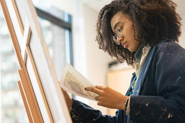 A student drawing onto a canvas standing on an easel