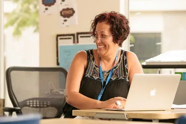 Smiling school staff member using a laptop